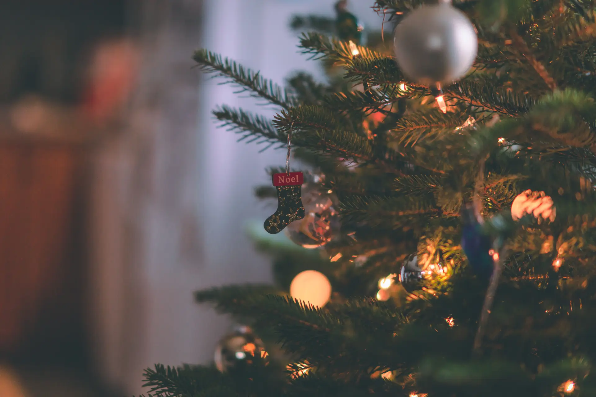 Christmas stockings and baubles on a lit Christmas tree