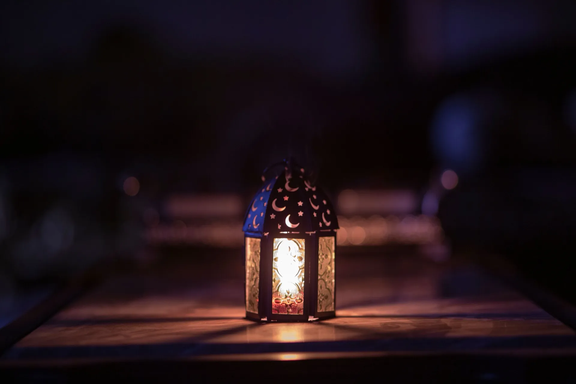 A lantern decorated with crescent moons glowing in the dark