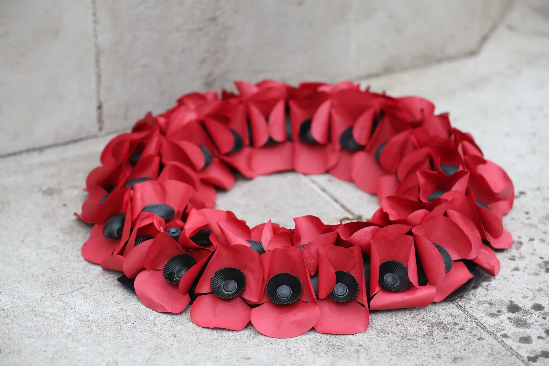 A wreath of red poppies at the foot of a stone memorial