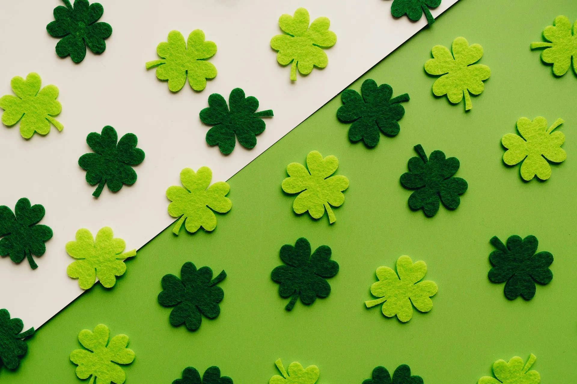 Light and dark green felt shamrocks on a green and white background