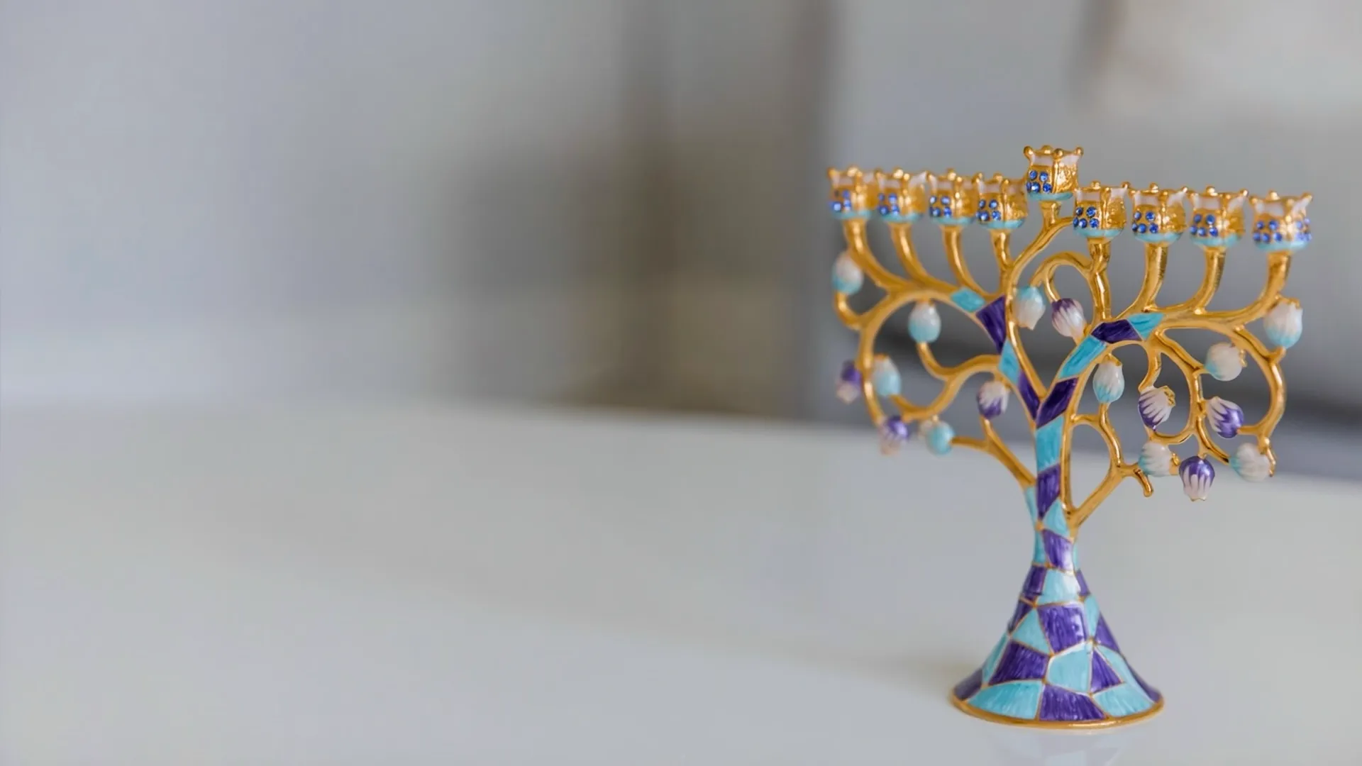 A gold and blue menorah on a white table